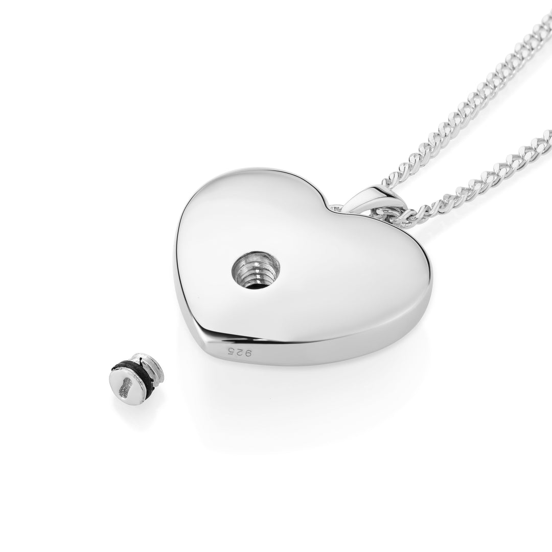 Silver heart with open hole and screw laying on a white surface