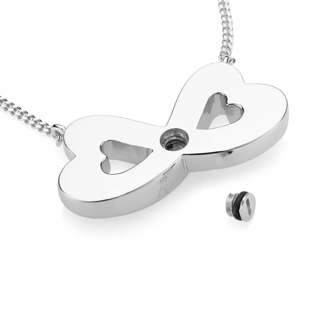 A silver infinity-shaped pendant necklace with two heart cutouts and a small screw fastener, shown on a white background with a small matching screw accessory nearby.