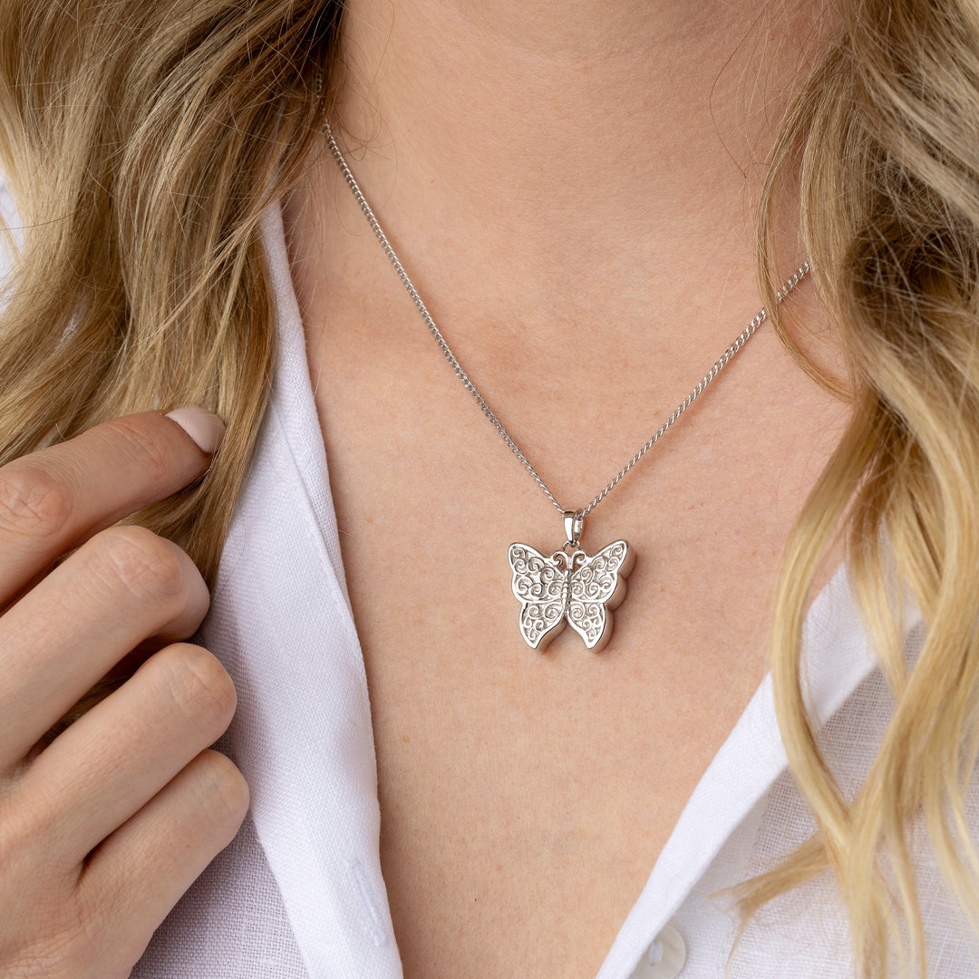 Butterfly necklace worn by a person with a white shirt