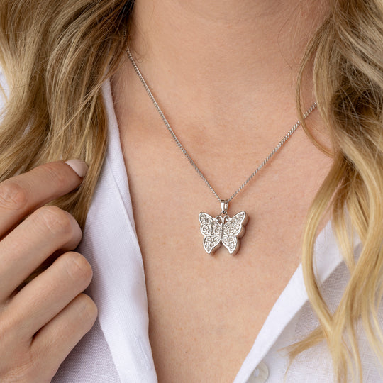 Butterfly necklace worn by a person with a white shirt
