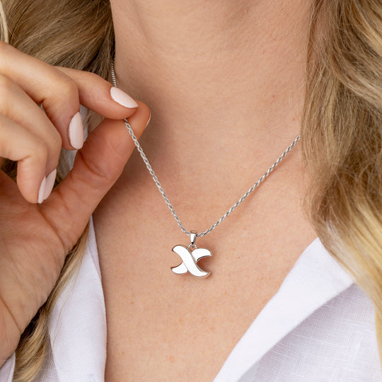Person wearing a silver necklace with a &