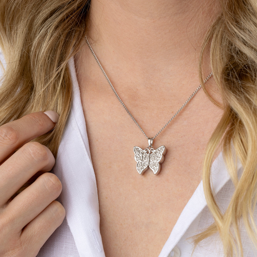 Butterfly necklace worn by a person with a white shirt
