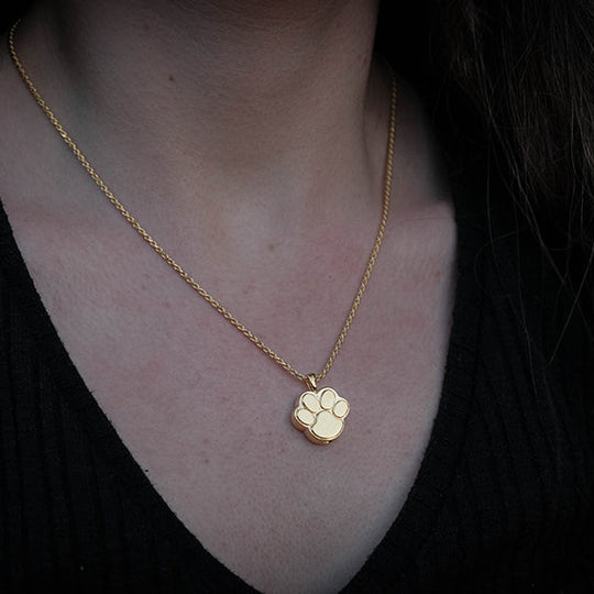 Gold necklace with a heart pendant worn by a person with long blonde hair.