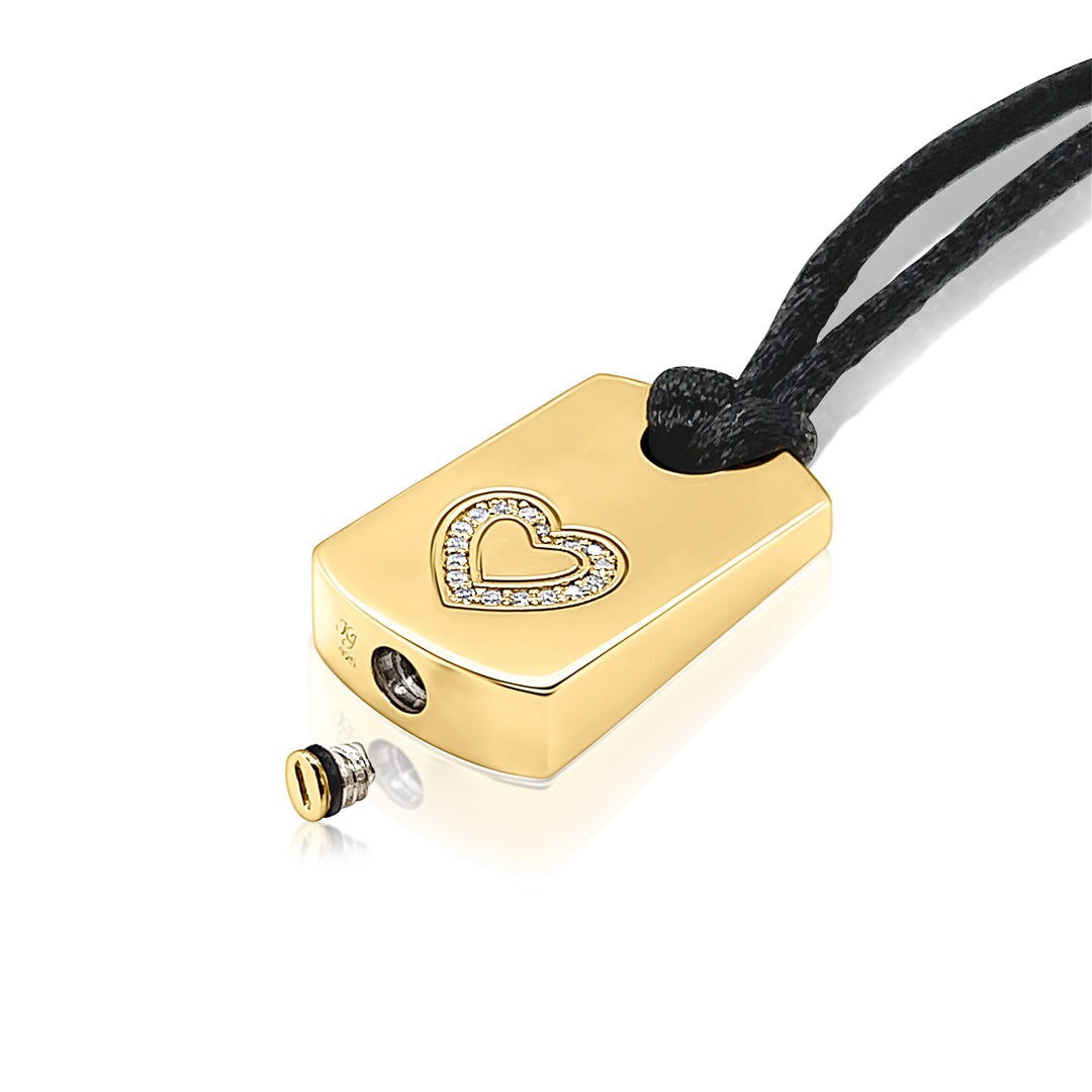 Gold rectangular pendant necklace with a heart-shaped crystal border and a black cord, shown on a white background with the small gold screw separated below.