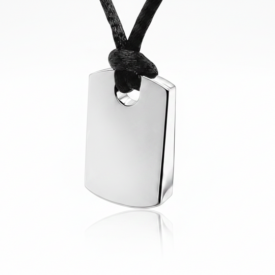 A polished silver military-style dog tag pendant on a black cord, shown against a clean white background with a soft reflection below.