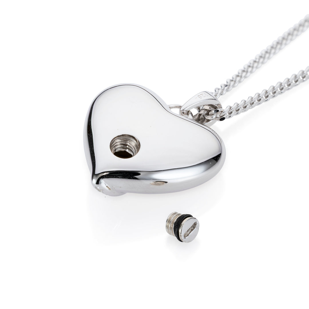 A silver heart-shaped pendant necklace on a matching chain, shown on a clean white background. The pendant has a small screw hole and a separate screw cap placed below it.