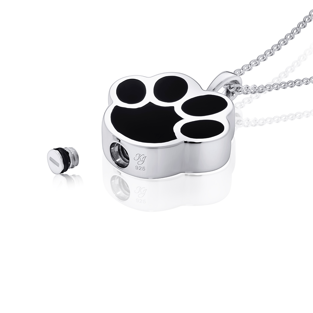 Photo showing black paw pet ashes pendant lying open displaying where pet cremation ashes are loaded.